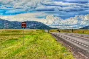 country road in wyoming with blue sky and mountains in the distance