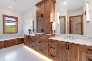 remodeled bathroom with white counters and floors and custom wood cabinetry