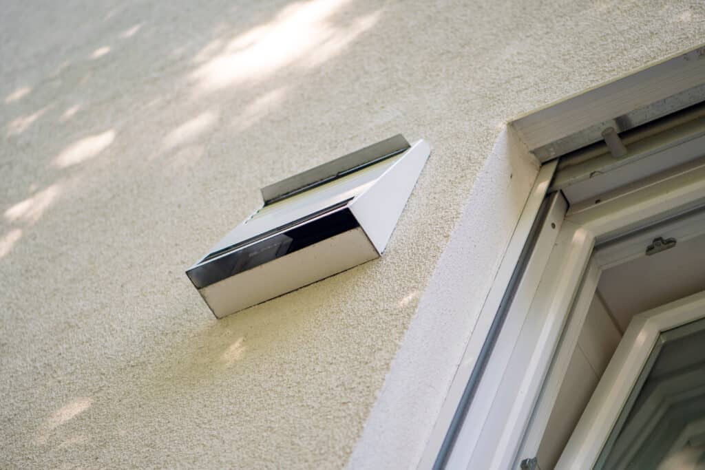 Heat recovery system (a small rectangular vent attached to a home exterior next to a window) for ventilating a house