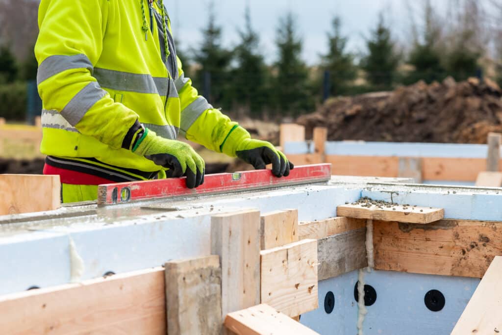 Construction Worker Using Level on Insulated Concrete Forms at Building Site